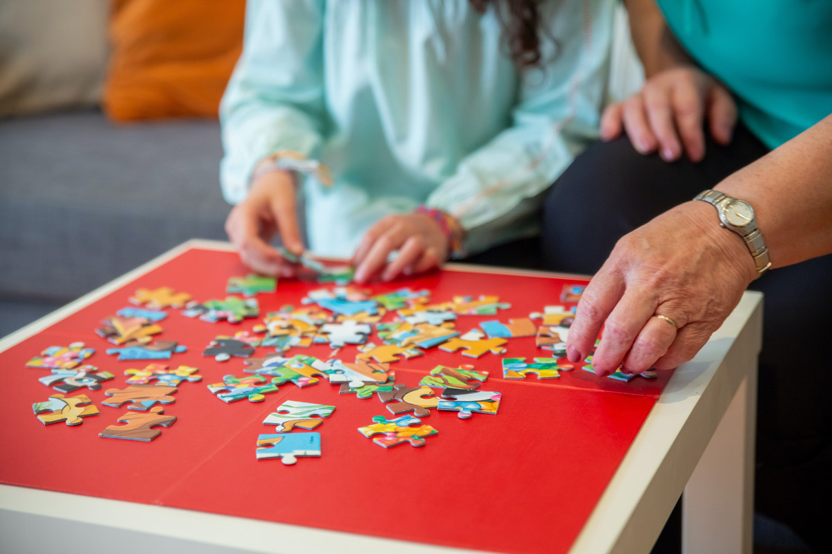 kid and adult assembling a puzzle together kid and adult assembling a puzzle together
